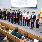 Uczniowie trzymają w rękach stypendia i stoją na scenie w towarzystwie prezydenta Tadeusz Truskolaskiego 