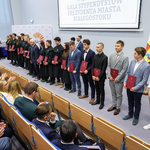 Podczas uroczystości wręczenia stypendiów prezydent Tadeusz Truskolaski stoi z uczniami na scenie auli
