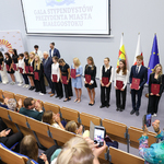 Uczniowie stoją z prezydentem Tadeusz Truskolaskim, na ekranie wyświetlana jest grafika 