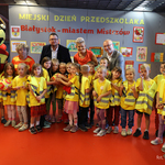 Przedszkolaki w kamizelkach odb;askowych stoją wspólnie z zastępca prezydenta Tomaszem Klim oraz kuratorem podlaskim Agnieszką Krokos-Janczyło