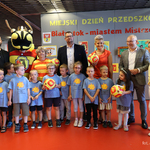 Dzieci w niebieskich bluzkach stoją wspolnie z opiekunem, zastępcą prezydenta Tomaszem Klim i kuratorem podlaskim Agnieszką Krokos-Janczyło