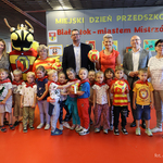 Grupa przedszkolaków z czerwonymi apaszkami na szyjach stoi razem z opiekunem, zastępcą prezydenta Tomaszem Klim i kuratorem podlaskim Agnieszką Krokos-Janczyło