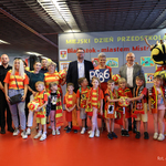 Grupa przedszkolaków w koszulkach i szalikach w barwach Jagiellonii stoi razem z opiekunem, zastępcą prezydenta Tomaszem Klim, kuratorem podlaskim Agnieszką Krokos-Janczyło i funkcjonariuszami Straży Miejskiej