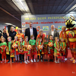 Grupa przedszkolaków w jasnozielonych koszulkach i z szalikamii w barwach Jagiellonii stoi razem z opiekunem, zastępcą prezydenta Tomaszem Klim i kuratorem podlaskim Agnieszką Krokos-Janczyło
