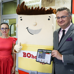 Zastępca prezydenta Rafał Rudnicki stoi po lewej stronie i trzyma tablet na którym wyświetlana jest strona internetowa miasta Białegostoku, po środku stoi maskotka Budżetu Obywatelskiego, po prawej stronie stoi dyrektor CAS Urszula Przystupa