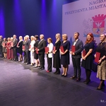Prezydent Tadeusz Truskolaski stoi z wyróżnionymi nauczycielami na scenie, w tle wyświetlana grafika 