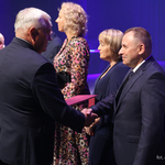 Prezydent Miasta Białegostoku podaje dłoń nauczycielowi na scenie, obok stoja inni uczestnicy wydarzenia 