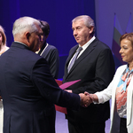 Prezydent Miasta Białegostoku gratuluje oraz podaje dłoń nauczycielce, obok stoi mężczyzna i inni uczestnicy 