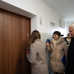 Prezydent Tadeusz Truskolaski stoi przed drzwiami do mieszkania z innimi uczestnikami wydarzenia 