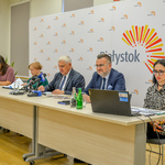 Prezydent Tadeusz Truskolaski, skarbnik Stanisława Kozłowska, rzecznik prasowy Urszula Buoblej i inni uczestnicy konferencji siedzą przy stole na którym stoją mikrofony