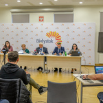 Prezydent Tadeusz Truskolaski, skarbnik Stanisława Kozłowska, rzecznik prasowy Urszula Buoblej i inni uczestnicy konferencji siedzą przy stole na którym stoją mikrofony, na pierwszym planie inni uczestnicy konferencji