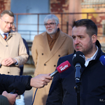 Przedstawiciel firmy budowlanej udziela wywiadu podczas konferencji prasowej, w tle stoją inni uczestnicy