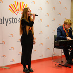 Kobieta śpiewa do mikrofonu, obok mężczyzna gra na pianinie.