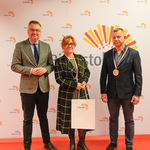 Zastępca prezydenta Rafał Rudnicki stoi z dwiema osobami wyróżnionymi medalami.
