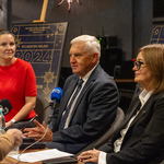 Prezydent Tadeusz Truskolaski mówi do mikrofonu podczas konferencji, obok siedzą dwie kobiety.