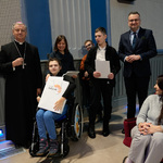 Zastępca prezydenta Rafał Rudnicki i duchowny stoją z laureatami konkursu którzy trzymają białe torby z logo Białegostoku.