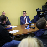 Zastępca prezydenta Marek Masalski siedzi przy stole z innymi uczestnikami, na pierwszym planie kamera.