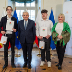 Dwóch uczniów z listami gratulacyjnymi w dłoniach stoją obok kobiety i prezydenta Tadeusza Truskolaskiego.
