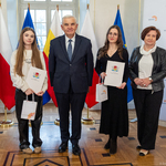 Dwie uczennice w listami gratulacyjnymi w dłoniach stoją obok kobiety i prezydenta Tadeusza Truskolaskiego.
