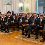 Uczestnicy uroczystości siedzą na krzesłach w Auli Magna UMB.