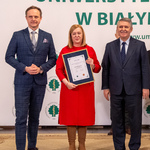 Kobieta trzyma dyplom, obok stoi prof. dr hab. n. med. Marcin Moniuszko oraz mężczyzna.