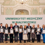 Dziesięcioro uczestników stoi trzymając dyplomy, obok stoi dwóch mężczyzn.