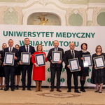 Dwanaście osób stoi w tym dziewięć trzyma dyplomy.