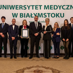 Kobieta trzyma dyplom, obok stoi kilka osób.