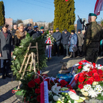 Przedstawiciele miasta i inni uczestnicy stoją przed Pomnikiem-Grobem Nieznanego Sybiraka na którym leżą kwiaty.