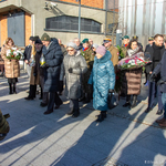 Uczestnicy uroczystości stoją z kwiatami i zniczami obok budynku Muzeum Pamięci Sybiru.