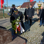 Zastępca prezydenta Tomasz Klim, marszałek Łukasz Prokorym oraz mundurowi stoją przed pomnikiem, jeden z oficerów kładzie kwiaty przed pomnikiem.