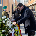 Zastępca prezydenta Tomasz Klim poprawia wstęgę przy kwiatach złożonych pod Pomnikiem Matek Sybiraczek.