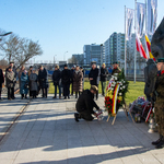 Uczestnicy uroczystości stoją pod Pomnikiem Matek Sybiraczek.
