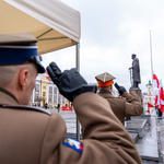 Mundurowi salutują zwróceni w stronę pomnika marszałka Józefa Piłsudskiego.