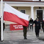 Żołnierze zakładają flagę Polski na maszt w trakcie uroczystości.