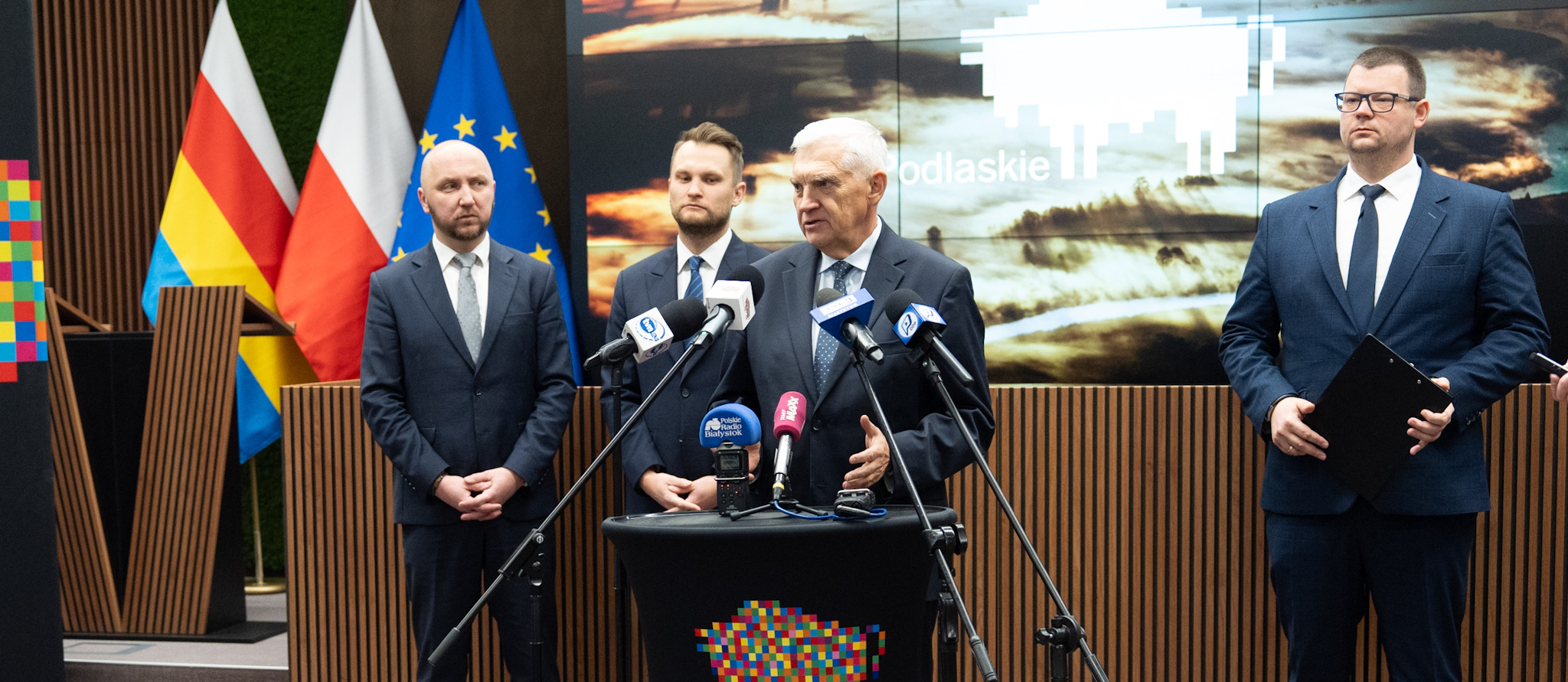 Prezydent Tadeusz Truskolaski przemawia do mikrofonów przy mównicy, obok stoją marszałek Łukasz Prokorym, zastępca prezydenta Tomasz Klim, poseł na Sejm RP Krzysztof Truskolaski.