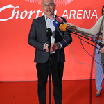 Prezes Chorten Areny Cezary Mielko mówi do mikrofonu podczas konferencji, obok stoją inni uczestnicy.