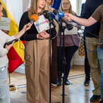 Przedstawicielka organizacji „My dla innych” mówi do mikrofonów, w tle stoją inni uczestnicy konferencji.