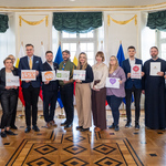Zastępca prezydenta Rafał Rudnicki stoi z przedstawicielami białostockich organizacji pozarządowych którzy trzymają tabliczkę z logo swojej organizacji.