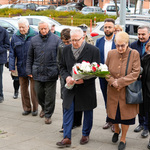 Grupa uczestników stoi na chodniku przy u. Sienkiewicza, mężczyzna trzyma bukiet kwiatów.