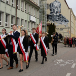 Poczet sztandarowy idzie obok budynku szkoły.
