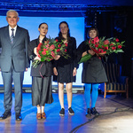 Prezydent Tadeusz Truskolaski stoi na scenie obok trzech kobiet które trzymają bukiety w dłoniach.