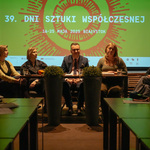 Uczestnicy konferencji siedzą przy stole, w tle wyświetlana grafika z tekstem „39. DNI DNI SZTUKI WSPÓŁCZESNEJ 16-25 MAJA 2025 BIAŁYSTOK”.
