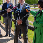 Dyrektor Muzeum Wojska w Białymstoku mówi do mikrofonów podczas konferencji prasowej, w tle stoją inni uczestnicy.