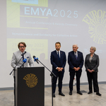 Dyrektor Muzeum Pamięci Sybiru Wojciech Śleszyński mówi do mikrofonu przy mównicy, w tle inni uczestnicy konferencji.