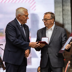 Mężczyzna odbiera nagrodę z rąk prezydenta Tadeusza Truskolaskiego.