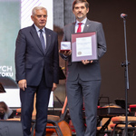 Na scenie stoi prezydent Tadeusz Truskolaski, obok stoi mężczyzna z nagrodą w rękach.
