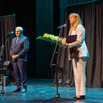 Kobieta trzyma bukiet kwiatów i mówi do mikrofonu, obok stoi prezydent Tadeusz Truskolaski.