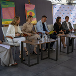 Kilkoro uczestników konferencji siedzi na krzesłach.