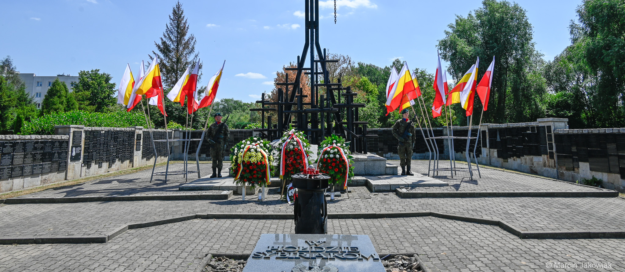Obok pomnika stoją mundurowi, ustawione są wieńce.